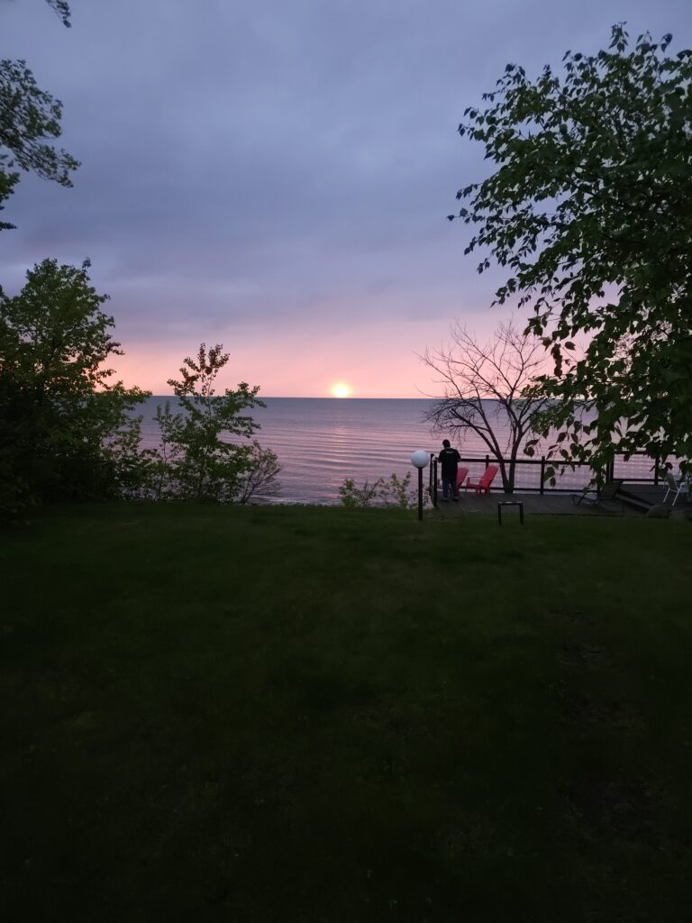A beautiful sunset over an open large body of calm water. A man is in between the person taking the photograph and the water, signifying that obstacles will try to block us from pursuing what we want.